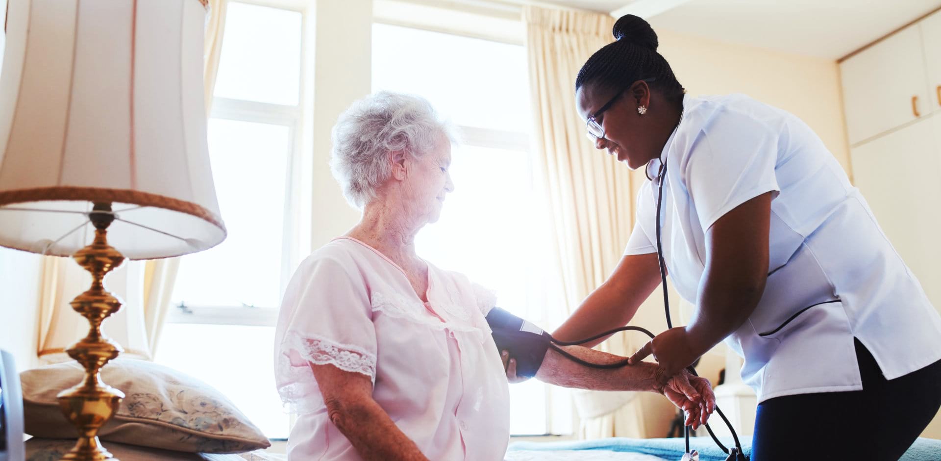 nurse checking blood pressure of a senior woman